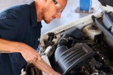 a mechanic checks the oil of a car